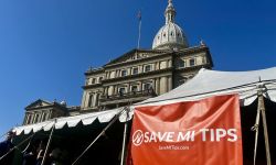 A sign says "Save MI Tips" in front of Michigan Capitol building.